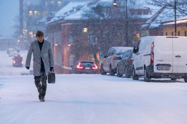 Stockholm, İsveç 3 Ocak 2024 Sundbyberg banliyösünde iyi giyimli bir adam kar fırtınasında yürüyor..