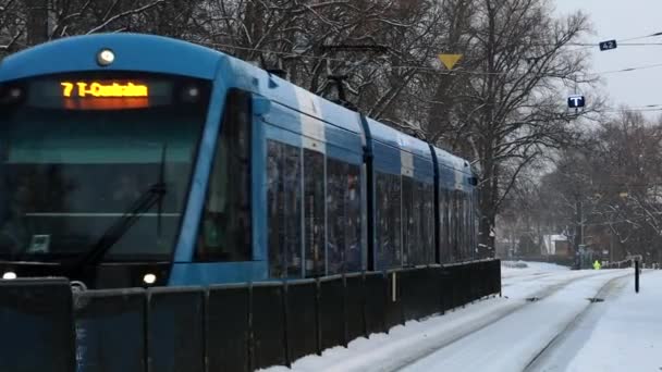 瑞典斯德哥尔摩一辆有轨电车驶向雪地上的一座车站 — 图库视频影像