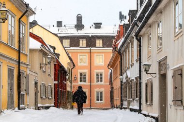 Stockholm, İsveç 4 Ocak 2023 kar altında Curgarden bölgesindeki eski evler. Breda Gatan 'da yürüyen yayalar..