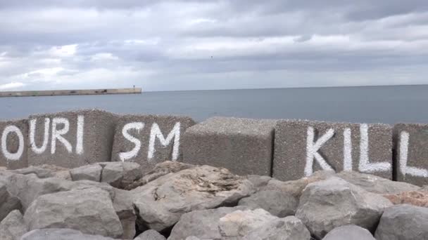 イタリアのシチリアのパレルモ 地中海の海岸に描かれたサインはこう述べています 観光が街を殺す — ストック動画