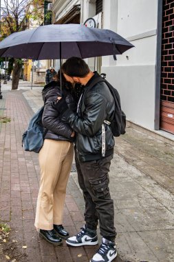 Palermo, Sicilya, İtalya 12 Ocak 2024 Yağmurda şemsiye altında öpüşen genç bir çift.