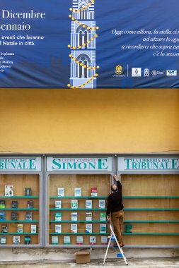 Palermo, Sicilya, İtalya 14 Ocak 2024 Bir adam bir binanın ön cephesinde cam bir kitap sergisi üzerinde çalışıyor.