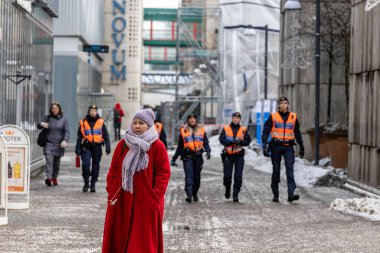 Stockholm, İsveç 26 Ocak 2024. Flemingsberg 'de yaya geçidinde yürüyen yaya bir kadın. Arka planda polis yürüyor..
