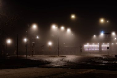 Stockholm, İsveç Liljeholmen banliyösünde bir sokak ve kavşağın gece sisli taraması.