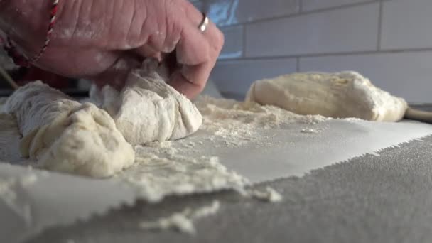 男は生地とワックスペーパーに小麦粉の家庭のキッチンでフランスのバゲットを作ります — ストック動画