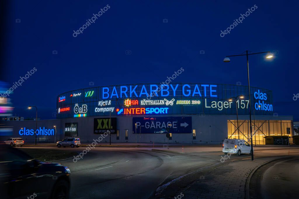 Stockholm, Sweden Feb. 4, 2024 The Barkaby Gate shopping mall and store signs at night with traffic.