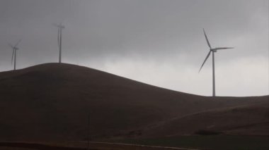 Yaka, Abruzzo, İtalya Yağmurda ve siste dağların tepelerinde rüzgar türbinleri dönüyor.