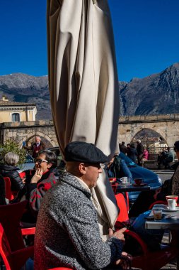 Sulmona, İtalya 18 Şubat 2024 Tipik şapkalı bir adam güneşli bir kafede oturur. Piazza Giuseppe Garibaldi 'de..