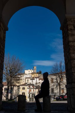İtalya 'dan Goriano Sicoli, Sihouette' de bir verandada oturuyor. Bu ortaçağ tepe kasabasının manzaralı bir kemerin altında..
