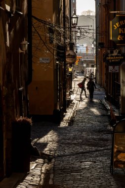 Stockholm, İsveç 6 Mart 2024 Eski Kasaba 'daki Gasgrand Ortaçağ geçidinde güçlü bir öğleden sonra güneşi altında bir kişi yürür..