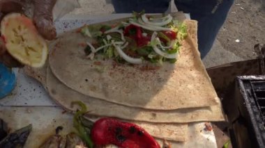 İstanbul, Türkiye 'de bir sokak yemeği satıcısı kızarmış balık sandviçi yapıyor. Düz ekmek, salata ve baharatla.. 