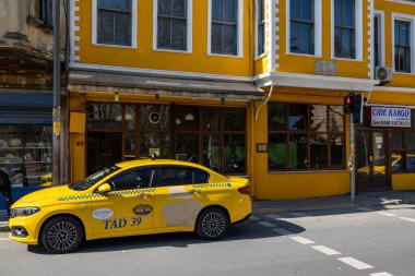 İstanbul, Türkiye 18 Mart 2024. Balat bölgesinde sarı bir evin önünde sarı bir taksi duruyor..