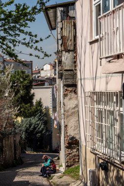 İstanbul, Türkiye 18 Mart 2024. Balat bölgesinde yaşlı bir kadın bir çocukla sokakta oturuyor..