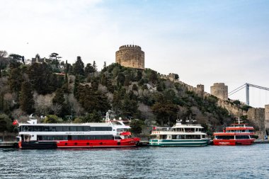 Istanbul, Turkey March 19, 2024 Ferry boats in Bosporus docked at the foot of the Rumeli Fortress. clipart