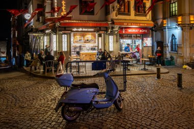 İstanbul, Türkiye 19 Mart 2024 Fransa 'dan esinlenilmiş şirin bir sokak sahnesi Galata' da bir kafe, insanlar ve scooterlı.