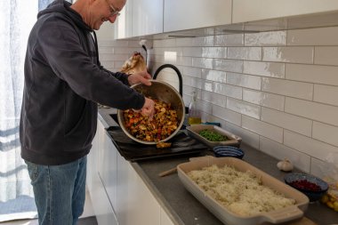 Bir adam modern bir mutfakta yemek hazırlar..