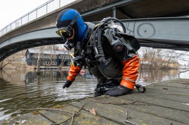 Stockhom, Sweden April  1, 2024 A scuba diver prepares to enter water   to pick up trash from the bottom of the Palsundet canal in downtown Stockholm. clipart