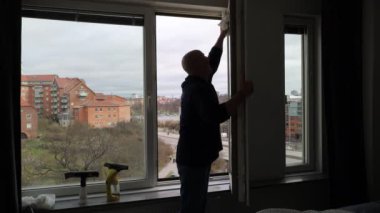 Stockholm, İsveç 'te bir adam bir apartmanın camlarını temizler.. 