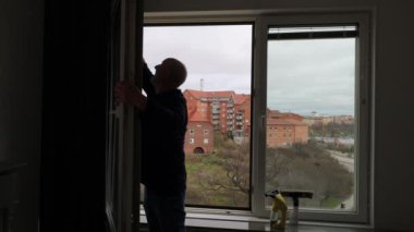 Stockholm, İsveç 'te bir adam bir apartmanın camlarını temizler.. 