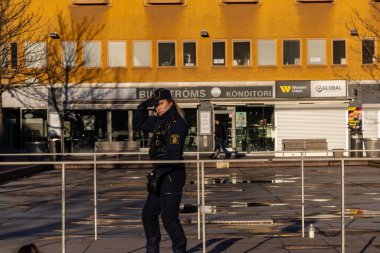 Stockholm, İsveç 12 Nisan 2024 Polis Skarholmen ehtnic banliyösünde genç çete üyeleri tarafından öldürülen bir adam için nöbet tutuyor..
