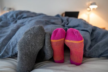 Yatak odasındaki yorganın altında bir kadın ve erkek.