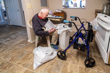 Solomons, Maryland, ABD 26 Mart 2024 Bir mutfakta kıdemli bir adam posta yoluyla çöp atıyor.