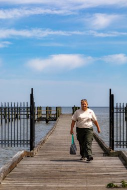 St. Clements Island, Maryland, USA April 29, 2024 A woman walks on a pier on the Potomac River. clipart