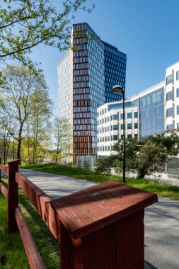 Stockholm, İsveç Gullmarsplan bölgesindeki Sthlm01 modern ofis binası ve bir park manzarası.