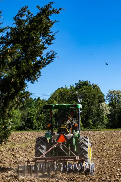 Broomes Adası, Maryland ABD, 1 Mayıs 2024 Güneşli bir günde bir traktör tarlayı sürüyor.