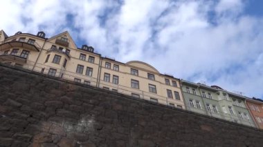 Stockholm, İsveç Rorstrandsgatan 'daki eski renkli apartman binaları ve büyük bir taş duvar.. 