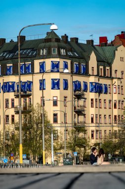 Stockholm, İsveç 12 Mayıs 2024 Tomtebodavagen 'da yeniden tasarlanmış bir köprüde genç bir çift halka açık banklarda oturuyor..