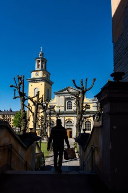 Stockholm, İsveç 21 Mayıs 2023. Bir adam 1645 'ten itibaren Sodermalm' daki Maria Magdalena Kilisesi 'ne doğru valiz taşıyıp yürüyor..