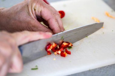 Bir aşçı kırmızı biberi kesme tahtasına dilimler..