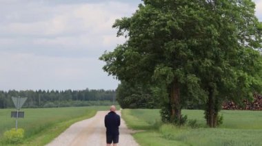 Tartu, Estonya Bir adam tarla boyunca uzun toprak bir yolda yürüyor.