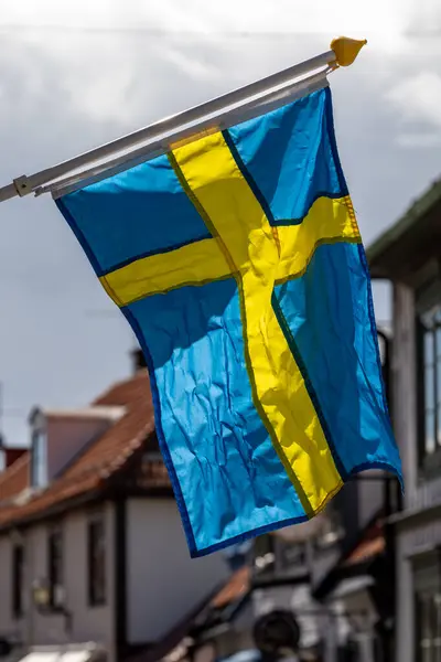 Stock image Sigtuna, Sweden June 14, 2024 A Swedish flag blowing in the wind on Stora Gatan.