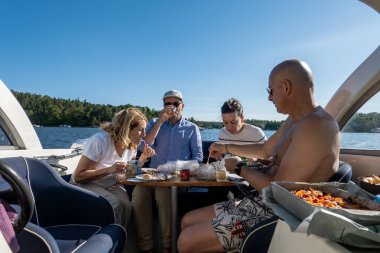 Stockholm, İsveç 21 Haziran 2024 Bir grup arkadaş yaz dönümünü kutlamak için teknede piknik yapıyorlar..