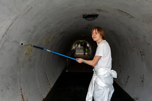 Stock image Stockholm, Sweden June 24, 2024 A teenage summer worker is  engaged in painting a pedestrian tunnel in the Fruangen district.