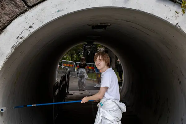 stock image Stockholm, Sweden June 24, 2024 A teenage summer worker is  engaged in painting a pedestrian tunnel in the Fruangen district.