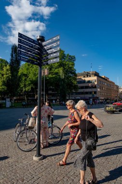 Gavle, İsveç 25 Haziran 2024 İnsanlar yön işaretleri altında ayakta ve yürüyorlar