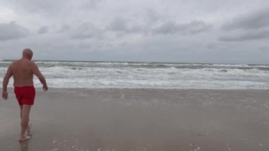 Hirtshals, Danimarka Kuzey Denizi sahilinde kırmızı şortlu bir adam yürüyor.. 