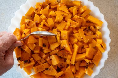 Baharatlı ve fırına hazır bir tabak çiğ ve doğranmış tereyağlı kabak..