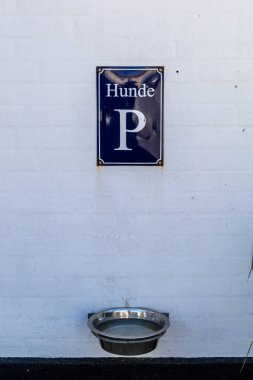 Lonstrup, Danimarka 'da bir su kasesi ve duvarda köpek park yeri yazan bir tabela..