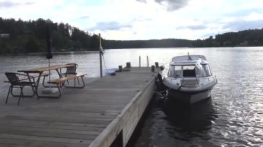 Stockholm, İsveç 'te bir kadın gün batımında Malaren Gölü' nde bir rıhtımda motorlu tekne kullanıyor..