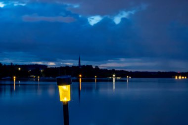 Stockholm, Sweden A small solar-powered night light illuminates the night view of Lake Malaren and the Ekero island coastline. clipart