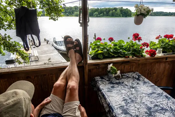 stock image Stockholm, Sweden A man relaxes with feet up on a small balcony overlooking a boat pier in Lake Malaren.