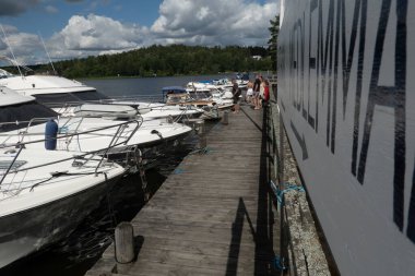 Stockholm, İsveç 20 Temmuz 2024 Bir ada rıhtımında insanlar ve özel sürat tekneleri ve İsveç dilinde üye tarafı ve üye olmayan tarafı işaret eden bir tabela.