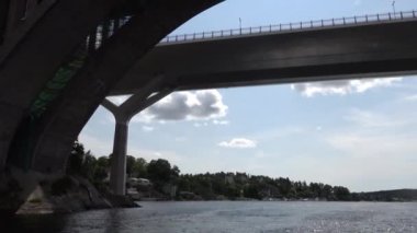 Stockholm, İsveç Nacka banliyösündeki Skurubron köprüsünün altından küçük bir tekne geçiyor.. 