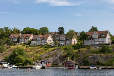 Stockholm, İsveç 26 Temmuz 2024 Nacka banliyösündeki Lannerstasundet su yolundaki ev ve tekneler.