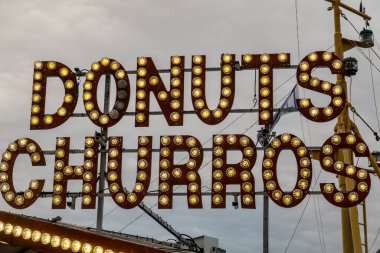 Stockholm, İsveç 28 Temmuz 2024 Donut ve Churros için sokak pazarında aydınlatılmış bir tabela.