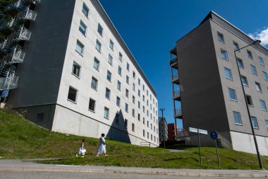 Stockholm, İsveç 30 Temmuz 2024 Visattra banliyösündeki modern apartmanlarda bir kadın ve kız çocuğu yürüyor..